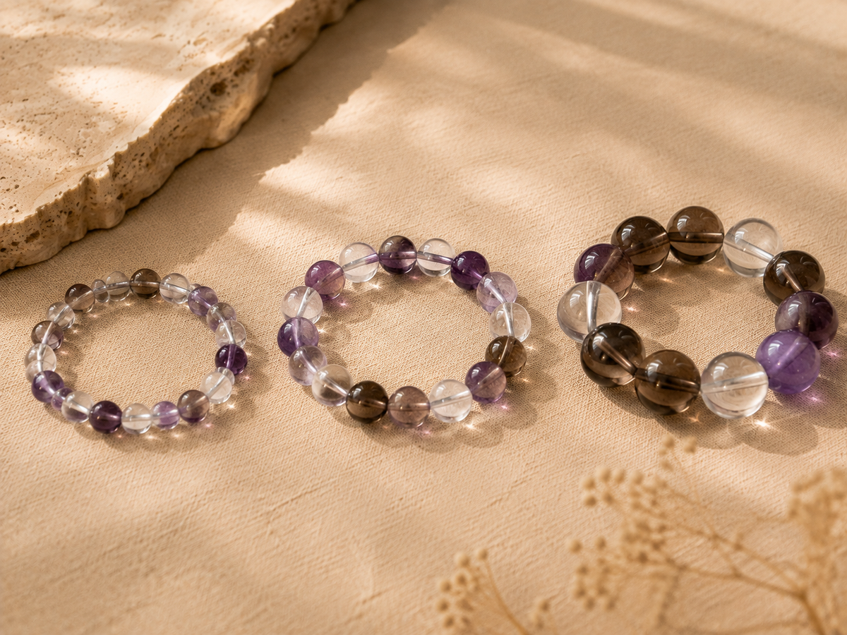 Crystal beads in 8mm 10mm and 12mm sizes arranged on a warm neutral surface