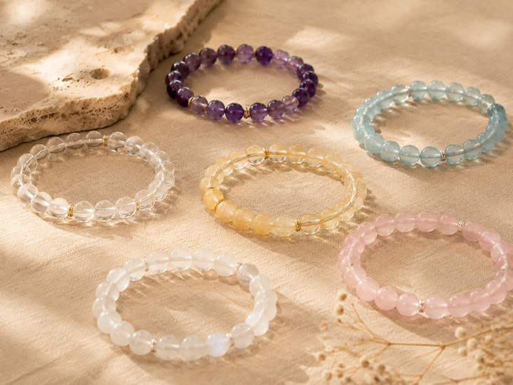 Birthstone crystal bracelets arranged on a warm neutral surface