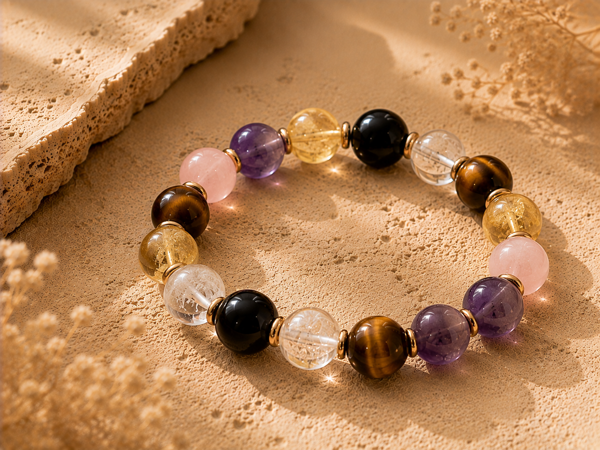 Aries crystal beads including tiger eye, citrine, clear quartz, black obsidian, amethyst, and rose quartz on a warm stone surface