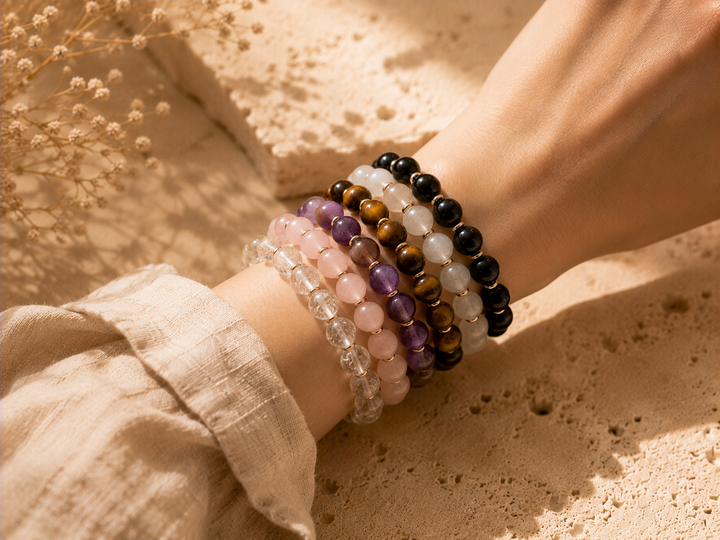 Crystal bracelets worn on a wrist with clear quartz, rose quartz, amethyst, tiger eye, moonstone, and black obsidian beads