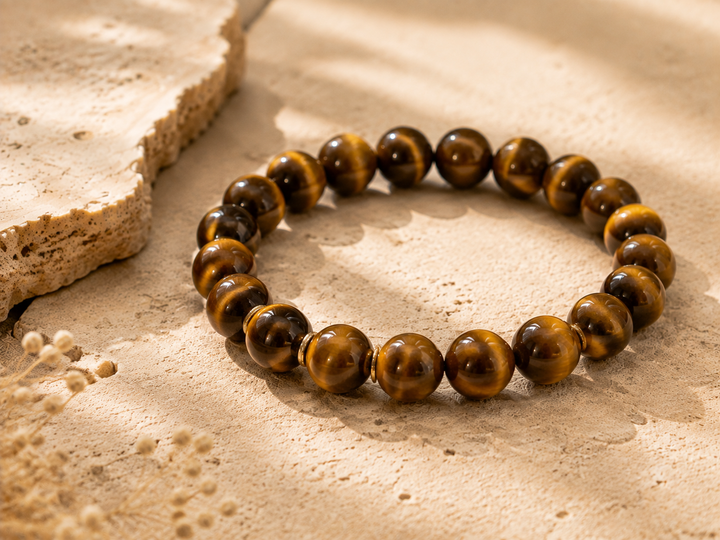 Tiger eye crystal beads with golden brown bands on a warm stone surface